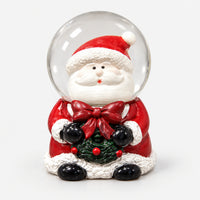 Santa Christmas snow globe holding a holly wreath with a red bow