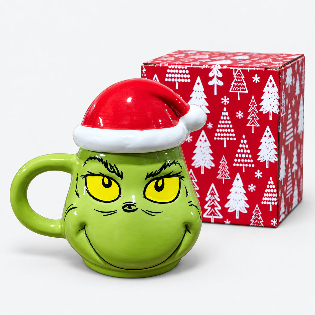 Green character mug with Santa hat lid next to its red Christmas tree gift box
