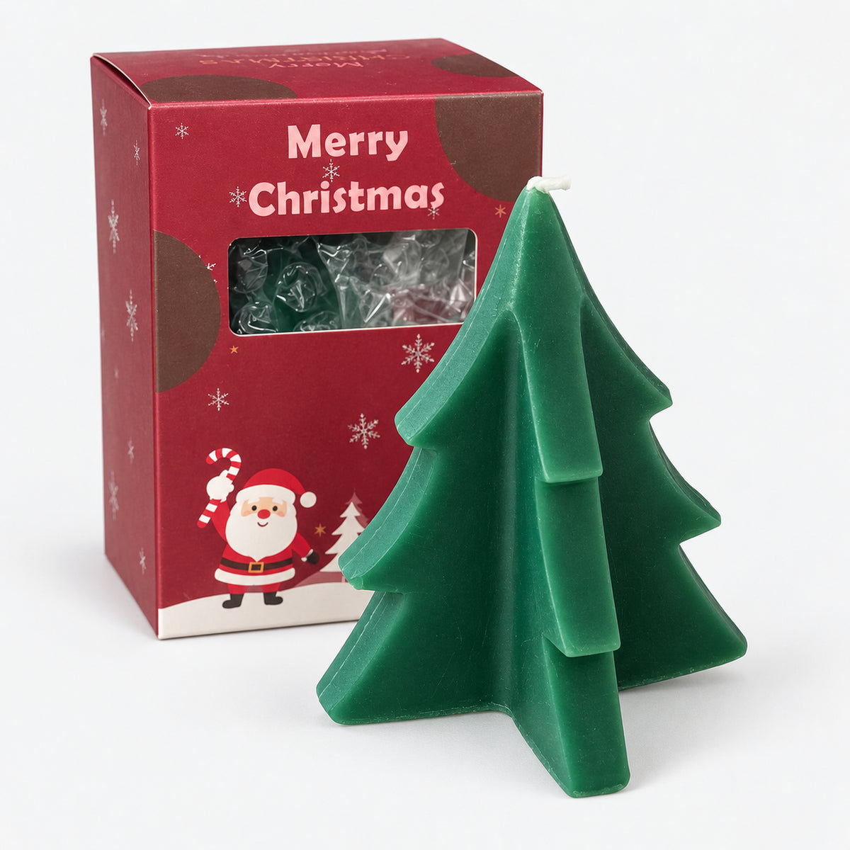 Green Christmas tree candle next to its red Merry Christmas gift box