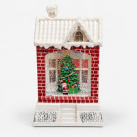 Christmas snowy house decoration with red brick walls and a Christmas tree in the window