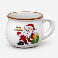 White rounded Christmas mug with Santa next to a green gift