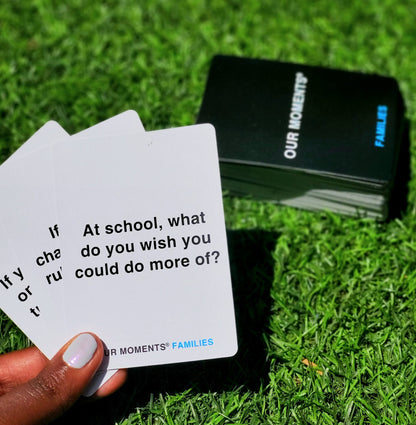 OUR MOMENTS Families question cards outdoors on the grass