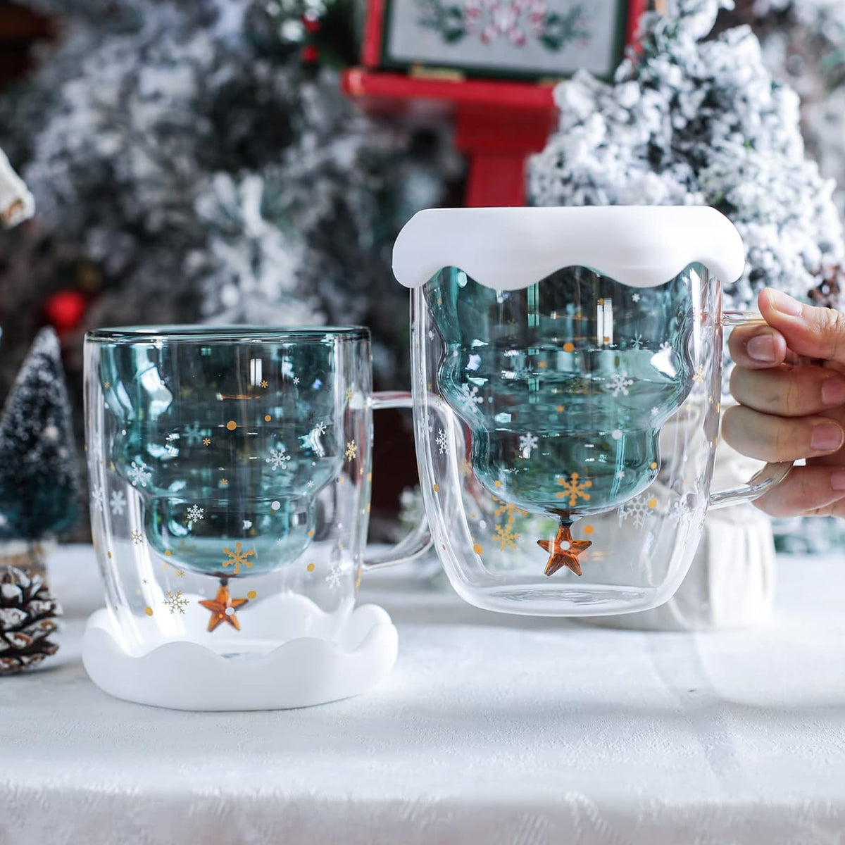 Two Christmas tree glass mugs with white snow silicone lids