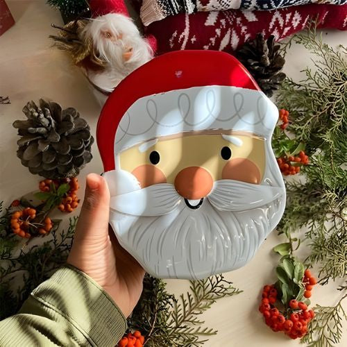 Santa face Christmas tin box held in a hand for size
