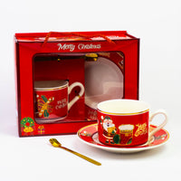 Christmas cup and saucer with gold spoon next to its red gift box