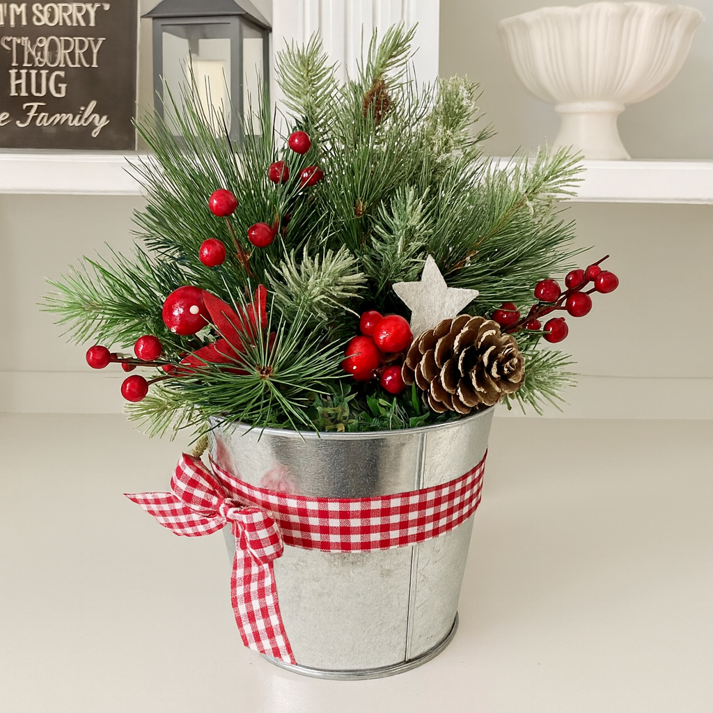 Artificial pine Christmas arrangement with red berries and a pine cone in a metal pot with a red gingham bow