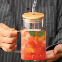 Hand holding a square glass jar with bamboo lid and glass straw