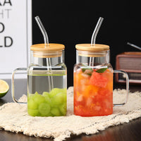 Two square glass mason jars with bamboo lids and glass straws filled with juice