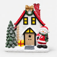 Snowy Christmas house decoration with a red roof, wreath, mini tree, gift and snowman