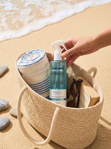 Elegance Sea Salt Spray in a straw beach bag on the sand