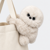 Beige plush bag charm hugging a tote bag strap