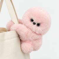 Pink plush bag charm hugging a bag strap