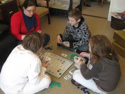 Family and kids playing the SEQUENCE board game on the floor