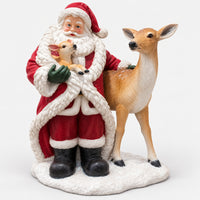 Santa figurine holding a baby fawn next to a doe on a snowy base