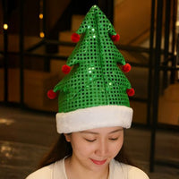 Woman wearing a green sequin Christmas tree party hat with red pom-poms